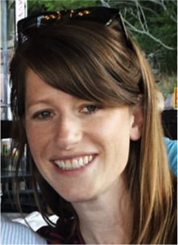 Casual close up of a smiling Lacey Hughey, her shoulder-length brown hair is down and she has sunglasses perched on her head.