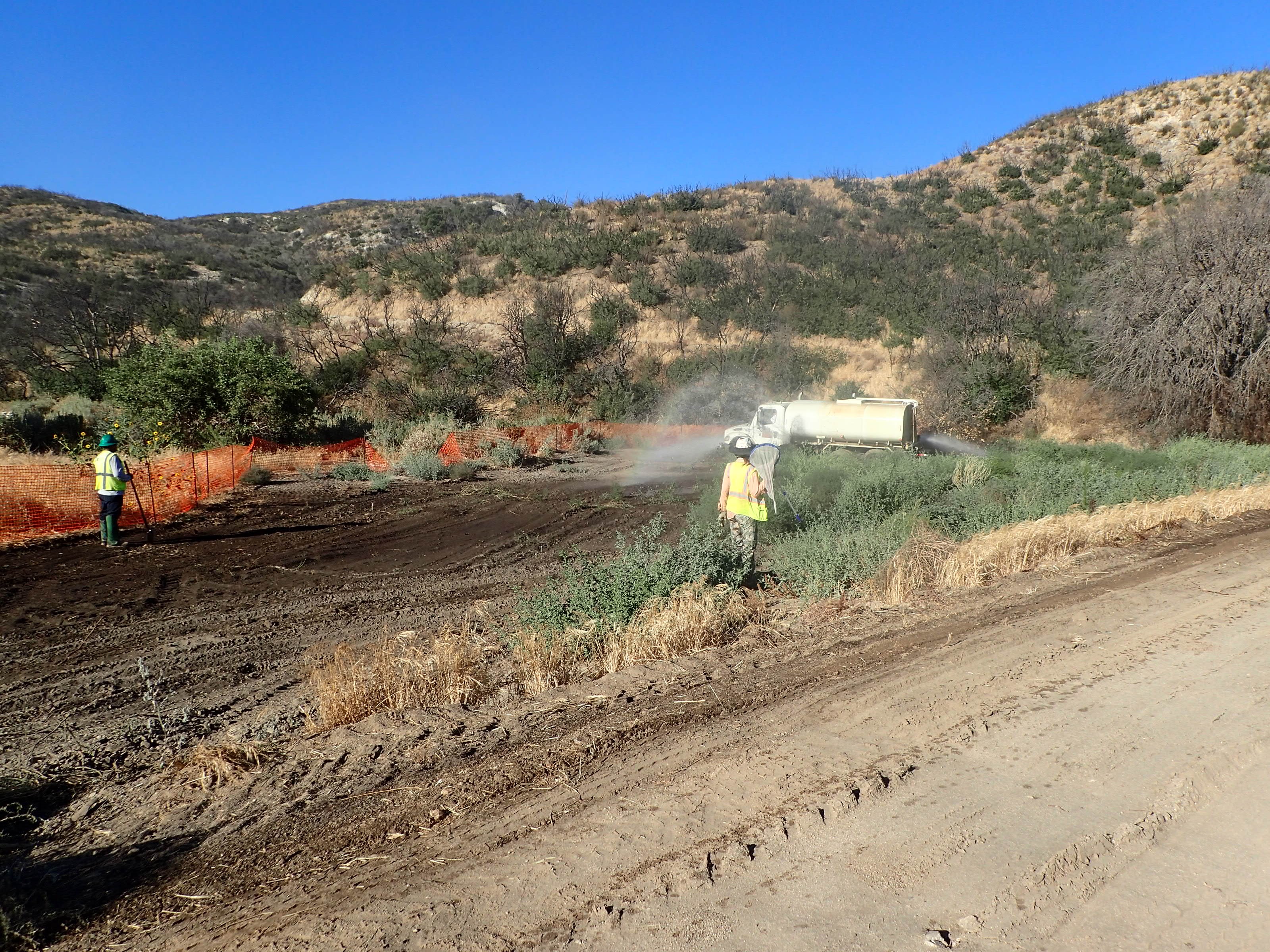 Image of wildlife biologist monitoring excavation and dust abatement at a mitigation bank resoration site.