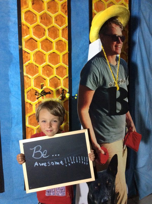 A child holding a sign that says "Be Awesome" next to a life-size cutout of Wildnote CEO Kristen Hazard 