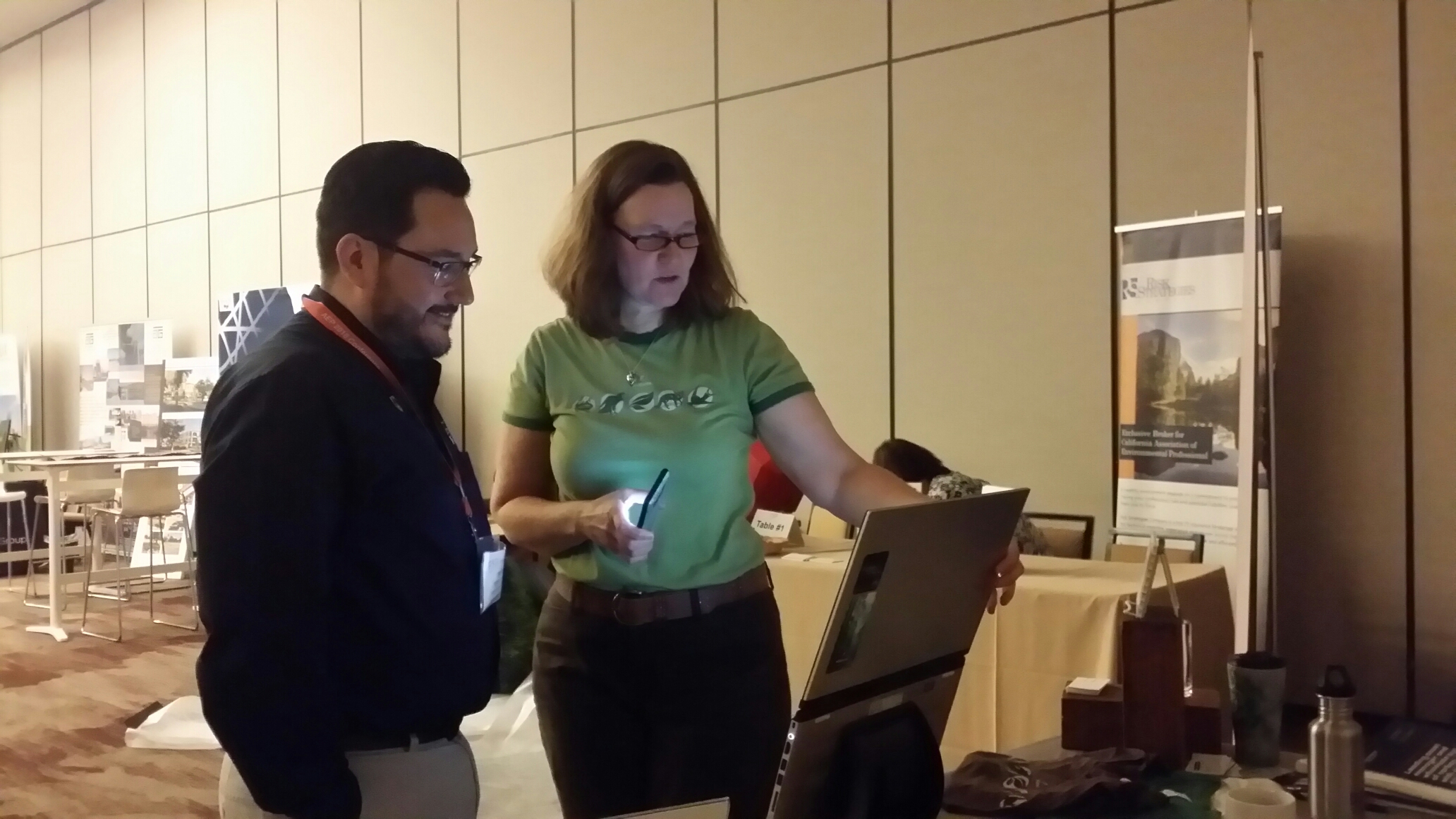 A woman and a man are standing and  looking at a laptop computer screen